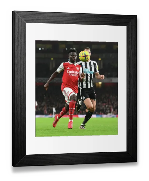 Framed Print : Arsenal's Bukayo Saka Takes on Newcastle's Dan Burn in Premier League Clash Framed Print : Arsenal's Bukayo Saka Takes on Newcastle's Dan Burn in Premier League Clash