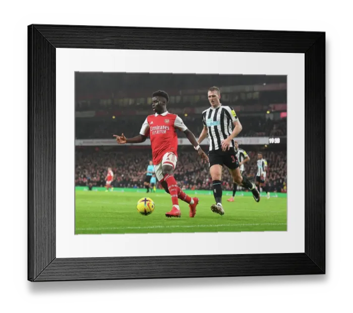 Framed Print : Arsenal's Bukayo Saka Goes Head-to-Head with Newcastle's Dan Burn in Premier League Battle Framed Print : Arsenal's Bukayo Saka Goes Head-to-Head with Newcastle's Dan Burn in Premier League Battle