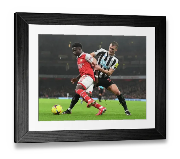 Framed Print : Arsenal's Bukayo Saka Fends Off Newcastle's Dan Burn in Premier League Clash Framed Print : Arsenal's Bukayo Saka Fends Off Newcastle's Dan Burn in Premier League Clash