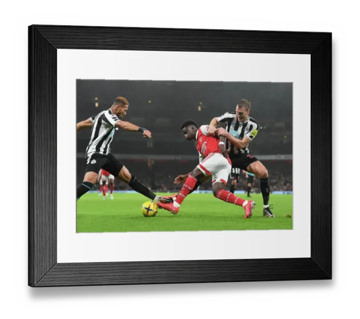 Framed Print : Arsenal's Bukayo Saka Fends Off Newcastle's Joelinton and Dan Burn during the Arsenal v Newcastle United Premier League Match, 2023