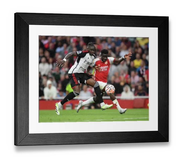 Framed Print : Arsenal's Bukayo Saka Clashes with Fulham's Calvin Bassey in Premier League Showdown at Emirates Stadium