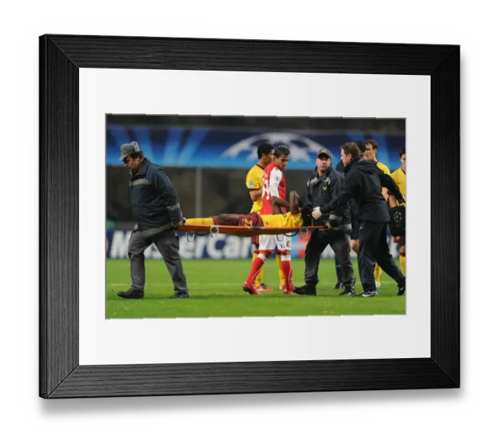 Framed Print : Arsenal defender Emmanuel Eboue is carried off after an injury to his ankle