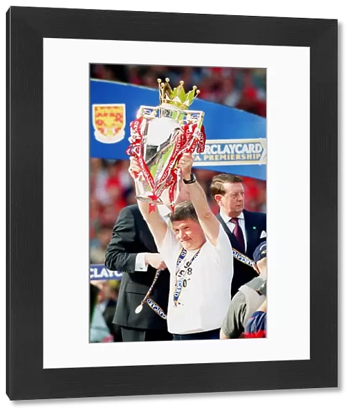Assistant manager Pat Rice lifts the F. A. Barclaycard Premiership Trophy