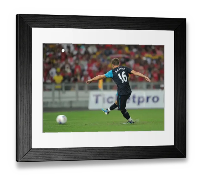 Framed Print : Aaron Ramsey shoots past Malaysia goalkeeper Khairul Che Mat to score the 1st Arsenal goal