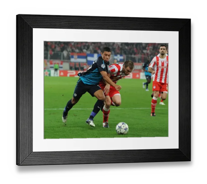 Framed Print : Alex Oxlade-Chamberlain vs. Avraam Papadopoulos: A Battle in the UEFA Champions League between Olympiacos and Arsenal