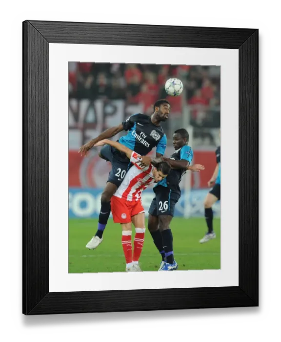 Framed Print : Arsenal's Johan Djourou Leaps Over Frimpong to Challenge Mirallas in Olympiacos Clash