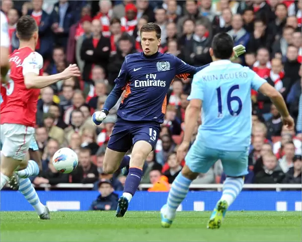 Wojciech Szczesny (Arsenal) clears the ball away from Sergio Aguero (Man City)