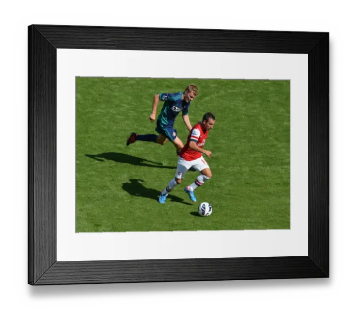 Framed Print : LONDON, ENGLAND - AUGUST 18: Santi Cazorla of Arsenal takes on Seb Larsson of Sunderland during the Barclays Premier League match between Arsenal and Sunderland at Emirates Stadium on August 18, 2012 in London, England. : Arsenal Football