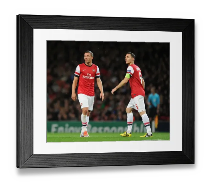Framed Print : Arsenal FC vs Olympiacos FC: Lukas Podolski and Thomas Vermaelen in Action during the 2012-13 UEFA Champions League Match