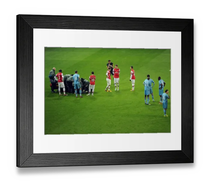 Framed Print : Arsenal and West Ham players wait for Daniel Potts (West Ham) to be treated for an injury Framed Print : Arsenal and West Ham players wait for Daniel Potts (West Ham) to be treated for an injury
