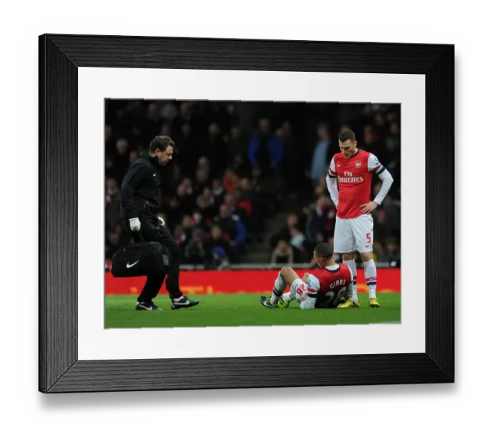 Framed Print : Kieran Gibbs (Arsenal) lies injured on the floor as Physio Colon Lewin races to help him Framed Print : Kieran Gibbs (Arsenal) lies injured on the floor as Physio Colon Lewin races to help him