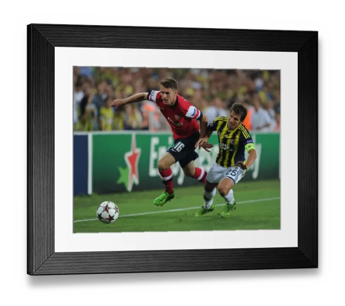 Framed Print : Arsenal's Aaron Ramsey Outmaneuvers Fenerbahce's Emre Belozoglu in UEFA Champions League Play-offs Clash