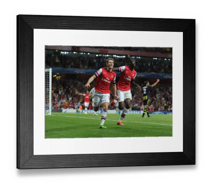 Framed Print : Arsenal Double Strike: Ramsey and Sanogo Celebrate Champions League Goals (2013-14)