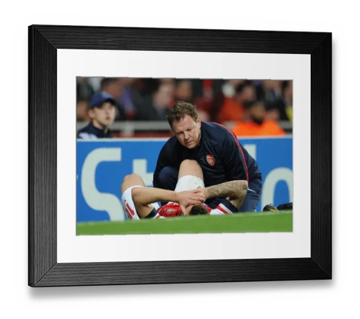 Framed Print : Arsenal: Jack Wilshere Receives Treatment from Colin Lewin vs Borussia Dortmund, UEFA Champions League (2013) Framed Print : Arsenal: Jack Wilshere Receives Treatment from Colin Lewin vs Borussia Dortmund, UEFA Champions League (2013)