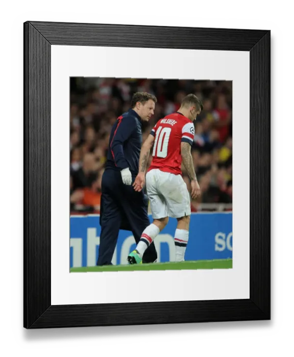 Framed Print : Arsenal's Jack Wilshere Receives Medical Attention from Physio Colin Lewin during UEFA Champions League Match against Borussia Dortmund (2013)