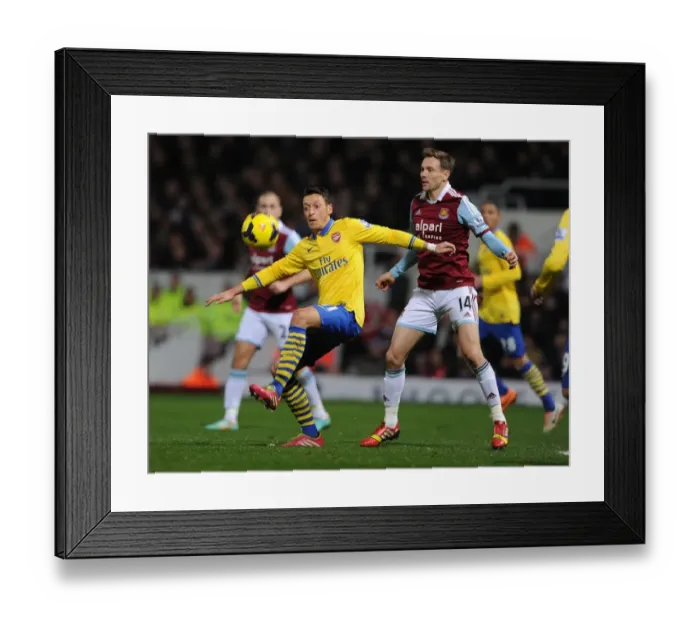 Framed Print : Mesut Ozil vs Matt Taylor: Battle at the Boleyn Ground - Arsenal vs West Ham United, Premier League, 2013