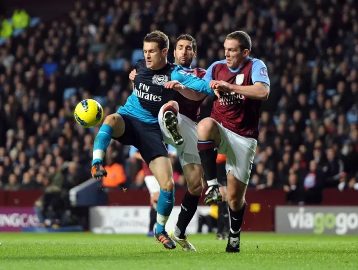 Framed Print : Aaron Ramsey Faces Off Against Carlos Cuellar and Richard Dunne in Intense Aston Villa vs. Arsenal Clash