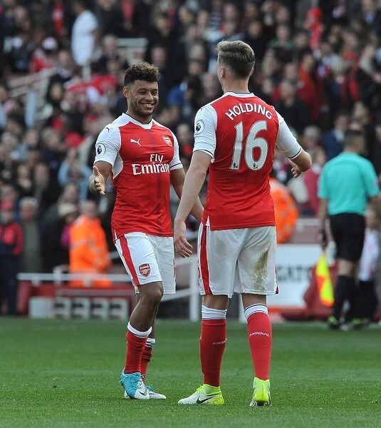 Arsenal Celebrate Victory: Oxlade-Chamberlain and Holding Embrace Post-Match at Emirates Stadium