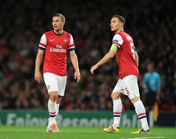 Arsenal FC vs Olympiacos FC: Lukas Podolski and Thomas Vermaelen in Action during the 2012-13 UEFA Champions League Match