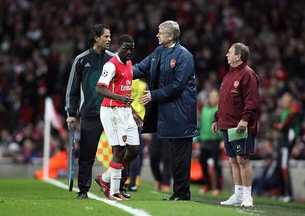 Arsenal manager Arsene Wenger pats Emmanuel Eboue on the back after his substitution