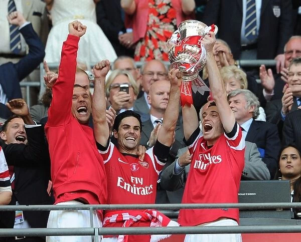 Arsenal Triumphs in FA Cup Final: Lukas Podolski, Mikel Arteta, and Thomas Vermaelen Lift the Trophy