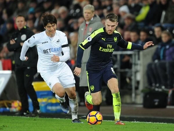 Arsenal's Aaron Ramsey Outmaneuvers Swansea's Ki Sung-Yueng in Premier League Clash