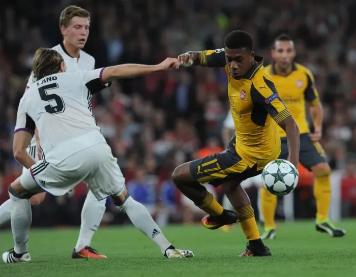 Framed Print : Arsenal's Alex Iwobi Battles Basel's Michael Lang in Champions League Showdown