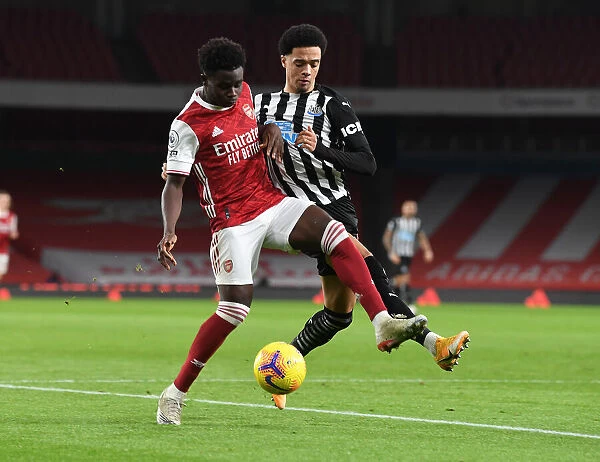 Arsenal's Bukayo Saka Battles Newcastle's Jamal Lewis in Empty Emirates Stadium