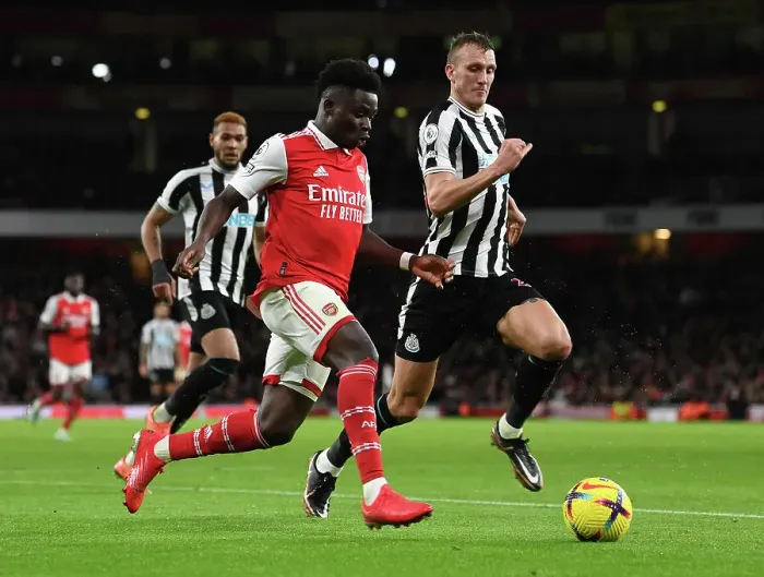 Framed Print : Arsenal's Bukayo Saka Clashes with Newcastle's Dan Burn in Premier League Showdown
