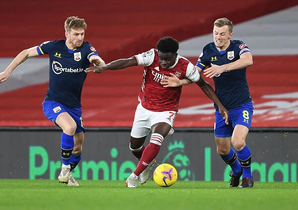 Arsenal's Bukayo Saka Faces Off Against Southampton Duo Stuart Armstrong and James Ward-Prowse in Emirates Stadium Showdown (2020-21)