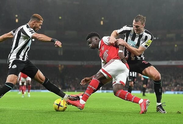 Arsenal's Bukayo Saka Fends Off Newcastle's Joelinton and Dan Burn during the Arsenal v Newcastle United Premier League Match, 2023