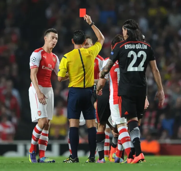Framed Print : Arsenal's Debuchy Dismissed: Koscielny Looks On as Proenca Shows Red in Arsenal v Besiktas Clash Framed Print : Arsenal's Debuchy Dismissed: Koscielny Looks On as Proenca Shows Red in Arsenal v Besiktas Clash