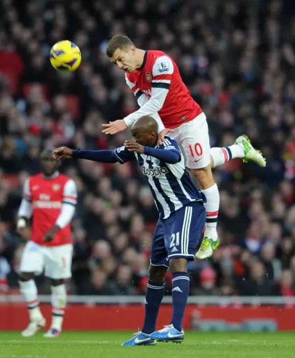 Framed Print : Arsenal's Jack Wilshere Leaps Over Youssouf Mulumbu (2012-13) Framed Print : Arsenal's Jack Wilshere Leaps Over Youssouf Mulumbu (2012-13)