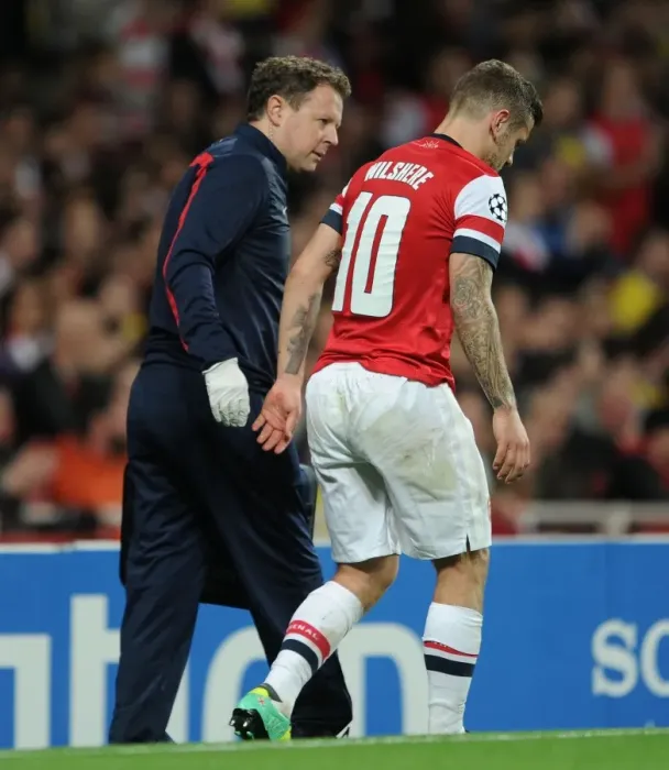Framed Print : Arsenal's Jack Wilshere Receives Medical Attention from Physio Colin Lewin during UEFA Champions League Match against Borussia Dortmund (2013)