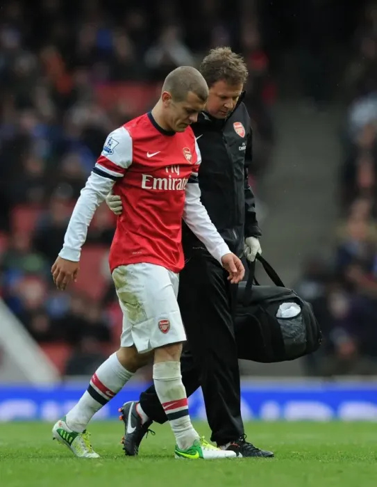 Framed Print : Arsenal's Jack Wilshere Receives Treatment from Physio Colin Lewin vs. Queens Park Rangers (2012-13)