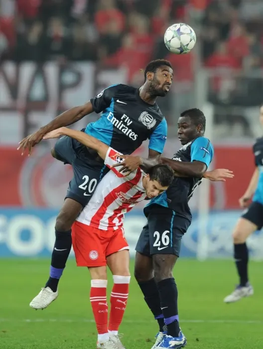 Framed Print : Arsenal's Johan Djourou Leaps Over Frimpong to Challenge Mirallas in Olympiacos Clash