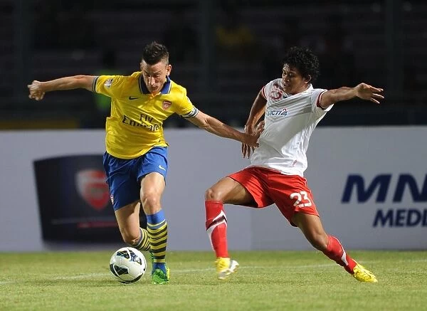 Arsenal's Laurent Koscielny Fends Off Indonesian Opponent During Pre-Season Match