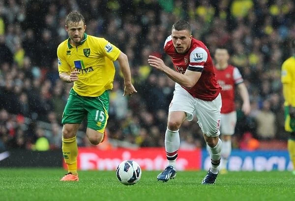 Arsenal's Lukas Podolski Outmaneuvers Norwich's David Fox in 2012-13 Premier League Clash
