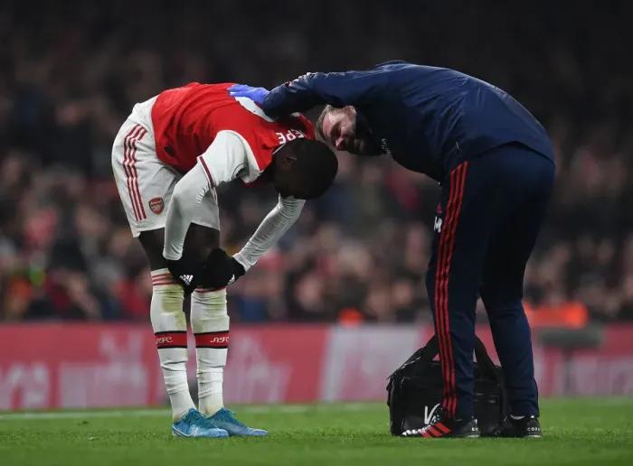 Framed Print : Arsenal's Nicolas Pepe Receives Treatment from Physio during Arsenal v Manchester United (2019-20)