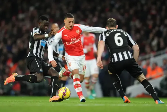Framed Print : Arsenal's Oxlade-Chamberlain Faces Off Against Newcastle's Tiote and Williamson in Intense Clash