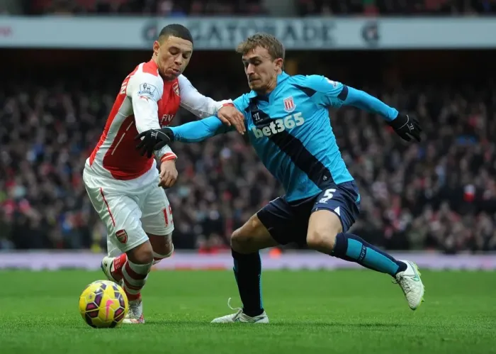 Framed Print : Arsenal's Oxlade-Chamberlain Faces Off Against Stoke's Muniesa in Premier League Clash