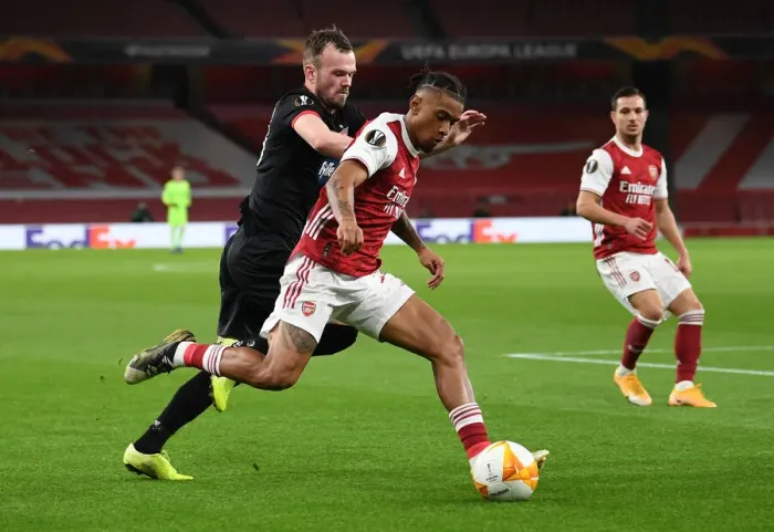 Framed Print : Arsenal's Reiss Nelson Clashes with Dundalk's Cameron Dummigan in Empty Emirates Stadium - UEFA Europa League 2020-21