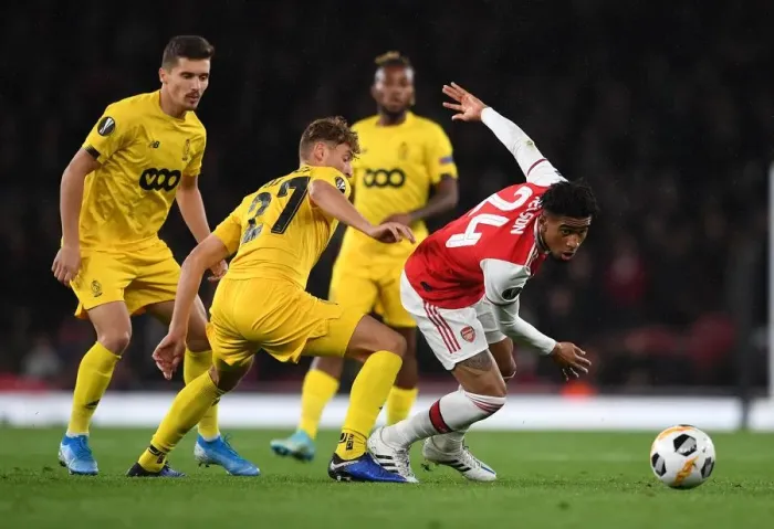 Framed Print : Arsenal's Reiss Nelson Faces Off Against Standard Liege's Mergim Vojvoda in UEFA Europa League Clash