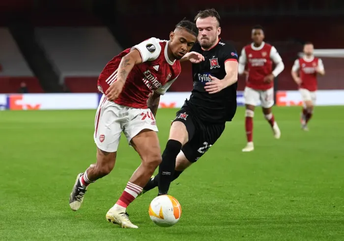 Framed Print : Arsenal's Reiss Nelson Goes Head-to-Head with Dundalk's Cameron Dummigan in Empty Emirates Stadium - UEFA Europa League 2020-21