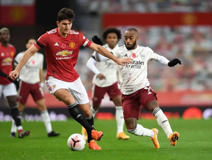 Framed Print : Clash at Old Trafford: Arsenal's Lacazette Pressures Maguire Amid Empty Stands (Manchester United vs Arsenal, 2020-21) Framed Print : Clash at Old Trafford: Arsenal's Lacazette Pressures Maguire Amid Empty Stands (Manchester United vs Arsenal, 2020-21)