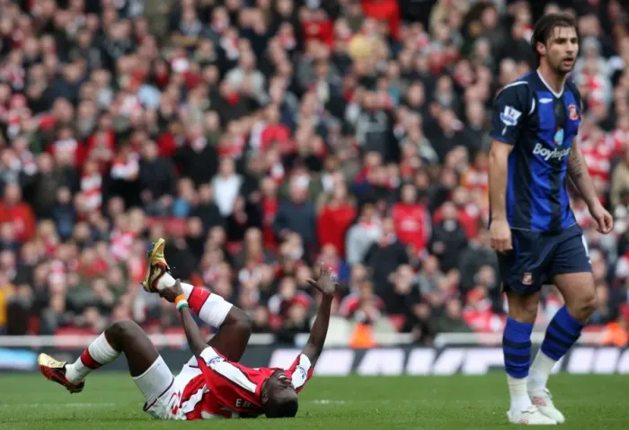 Framed Print : Emmanuel Eboue (Arsenal) holds his ankle following a challenge from Lorik Cana