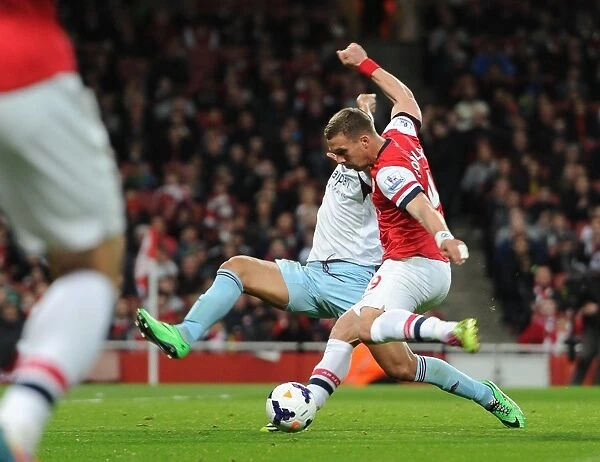 Lukas Podolski scores his and Arsenals 1st goal under pressure from Winston Reid (West Ham)
