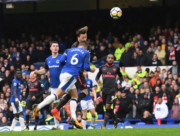 Framed Print : Mesut Ozil Scores Under Pressure: A Intense Moment from Everton vs Arsenal, Premier League 2017-18 - Ozil's Goal Amidst Jagielka's Challenge