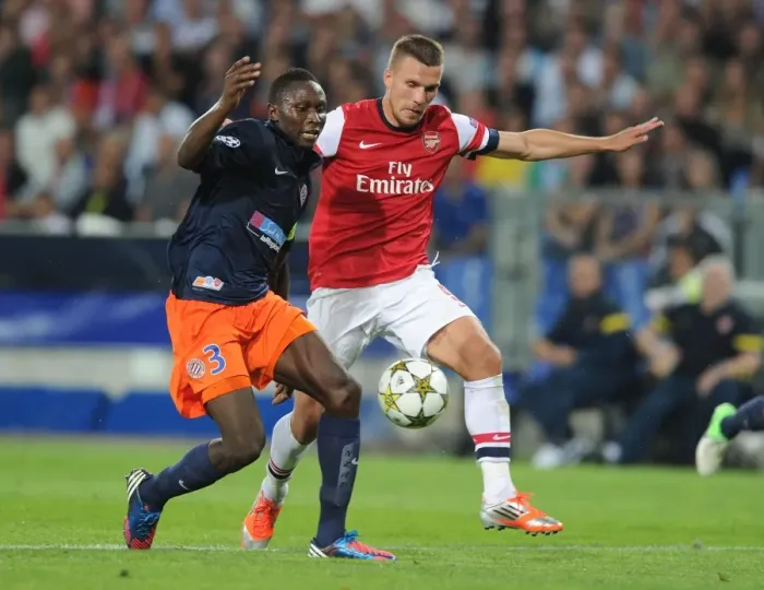 Framed Print : Podolski vs Yanga-Mbiwa: Battle in the UEFA Champions League