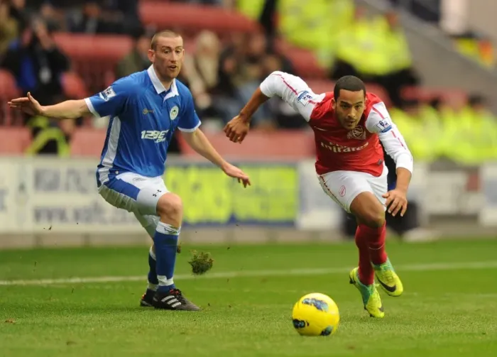 Framed Print : Theo Walcott Surges Past Wigan's David Jones in Premier League Clash (Wigan Athletic vs Arsenal, 2011-12) Framed Print : Theo Walcott Surges Past Wigan's David Jones in Premier League Clash (Wigan Athletic vs Arsenal, 2011-12)